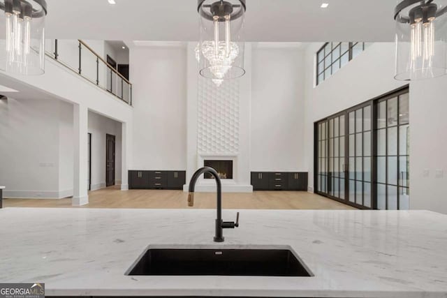 245 Traditions Dr, Alpharetta, GA 30004 - kitchen with a high ceiling, a large fireplace, light stone counters, a chandelier, and decorative light fixtures