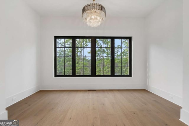 245 Traditions Dr, Alpharetta, GA 30004 - spare room featuring plenty of natural light, wood finished floors, and a chandelier