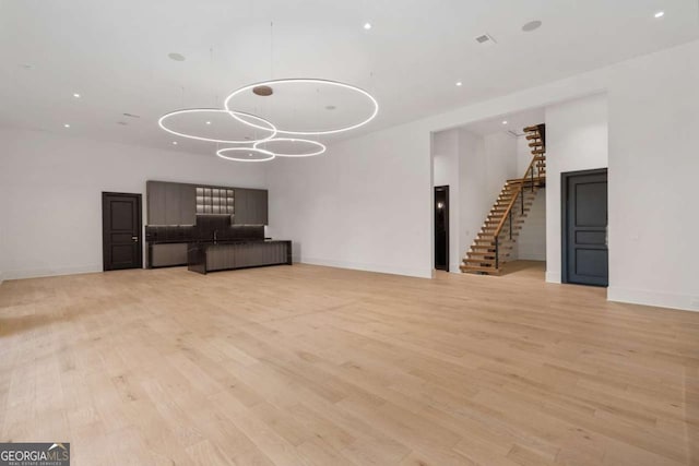 245 Traditions Dr, Alpharetta, GA 30004 - unfurnished living room featuring stairway, light wood finished floors, recessed lighting, and a chandelier