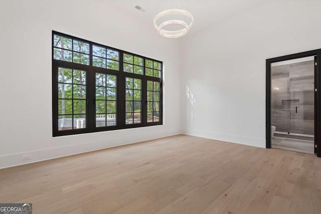 245 Traditions Dr, Alpharetta, GA 30004 - unfurnished room featuring a chandelier, wood finished floors, and healthy amount of natural light