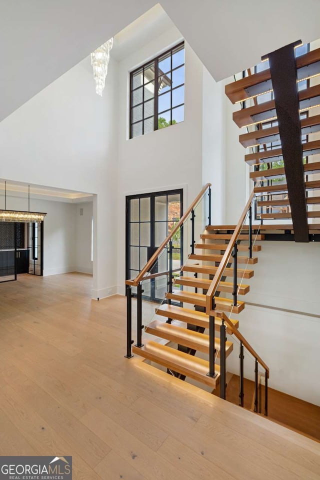 245 Traditions Dr, Alpharetta, GA 30004 - stairs with a towering ceiling, hardwood / wood-style floors, and a chandelier