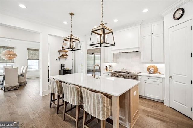 1057 Crossroads Trl, Milton, GA 30004 - kitchen featuring premium appliances, wood finished floors, an island with sink, light countertops, and recessed lighting