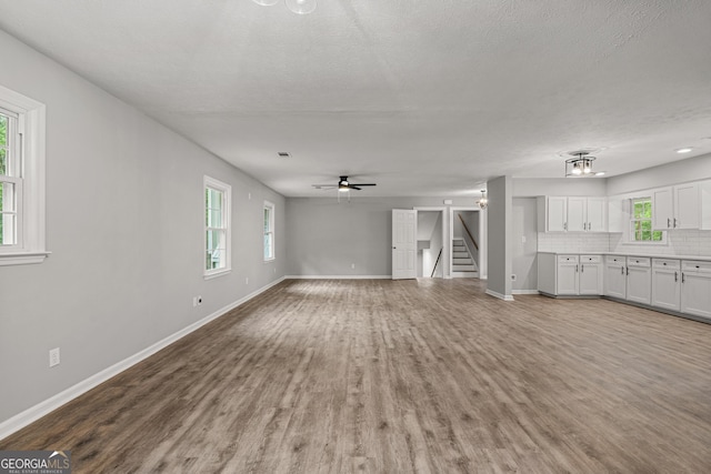 1000 Jones Rd, Cataula, GA 31804 - unfurnished living room with baseboards, wood finished floors, stairway, a ceiling fan, and a textured ceiling