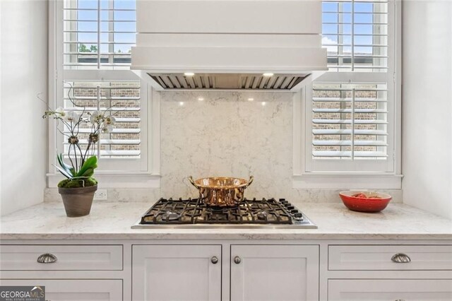 5971 Brundage Ln, Norcross, GA 30071 - kitchen with stainless steel gas stovetop, premium range hood, white cabinetry, and light stone countertops