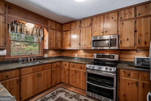 371 Little Rock Creek Ct, Cherry Log, GA 30522 - kitchen featuring stainless steel appliances, a textured ceiling, a sink, brown cabinets, and light wood-style floors