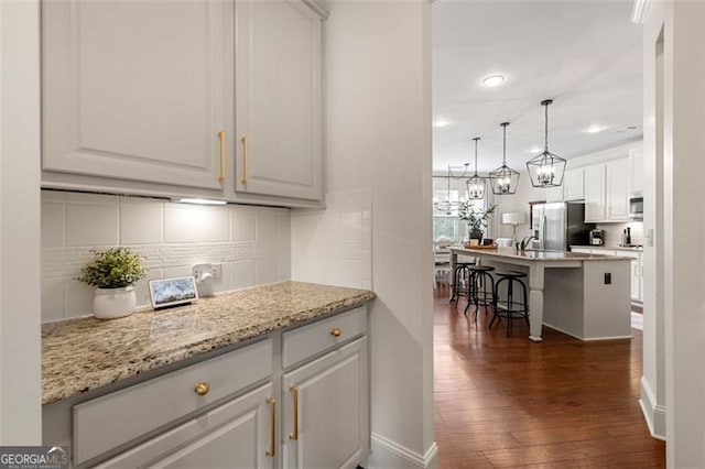 2680 Augeron Ct, Alpharetta, GA 30004 - kitchen with stainless steel appliances, dark wood-type flooring, white cabinetry, backsplash, and a kitchen breakfast bar