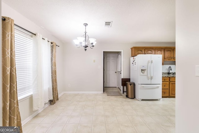 76 Duke Ln, Kathleen, GA 31047 - kitchen with white fridge with ice dispenser, a chandelier, brown cabinets, and healthy amount of natural light