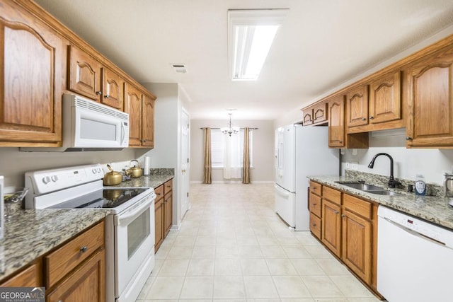 76 Duke Ln, Kathleen, GA 31047 - kitchen with white appliances, a chandelier, brown cabinetry, light stone counters, and light tile patterned flooring