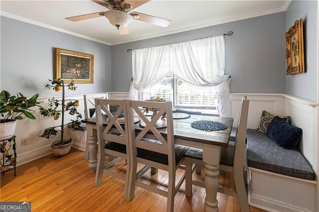 2050 Lyda Ln, Loganville, GA 30052 - dining room featuring crown molding, light wood-type flooring, a ceiling fan, a decorative wall, and a wainscoted wall