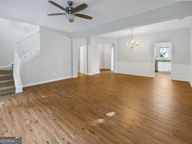 2555 Flat Shoals Rd Unit 3405, Atlanta, GA 30349 - unfurnished living room with a chandelier, stairs, light wood finished floors, a ceiling fan, and a wainscoted wall