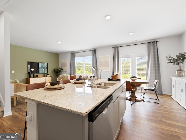 8215 Coldstream Dr, Fairburn, GA 30213 - kitchen featuring stainless steel dishwasher, an island with sink, wood finished floors, light stone counters, and recessed lighting