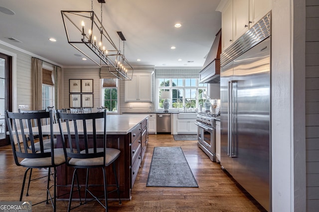 3315 Chandler Rd, Good Hope, GA 30641 - kitchen with high end appliances, dark wood finished floors, white cabinetry, a kitchen bar, and tasteful backsplash