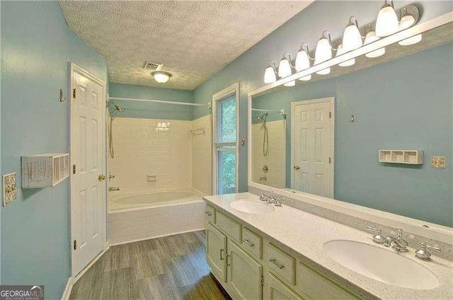 2212 Mcquiston Dr SW, Marietta, GA 30064 - bathroom featuring wood finished floors, tiled shower / bath combo, double vanity, and a textured ceiling