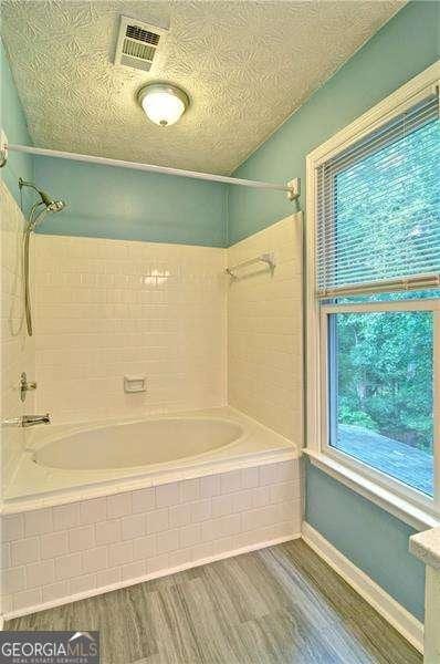 2212 Mcquiston Dr SW, Marietta, GA 30064 - full bath featuring wood finished floors, shower / washtub combination, and baseboards