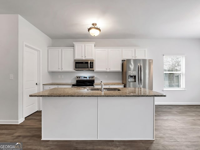 789 Galveston Way, Mcdonough, GA 30253 - kitchen featuring stainless steel appliances, baseboards, dark stone counters, an island with sink, and white cabinetry