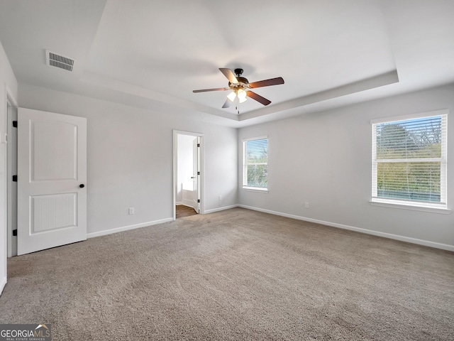 789 Galveston Way, Mcdonough, GA 30253 - unfurnished bedroom with a tray ceiling, carpet, baseboards, connected bathroom, and a ceiling fan