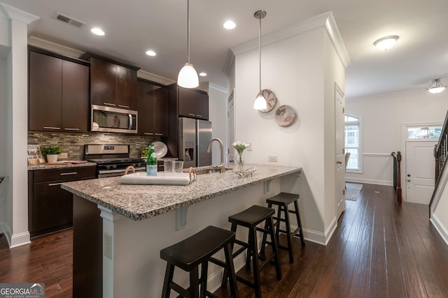 7850 Willoughby Ct, Alpharetta, GA 30005 - kitchen with stainless steel appliances, a kitchen bar, ornamental molding, a peninsula, and dark brown cabinets