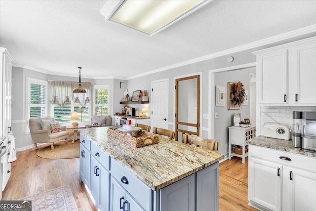 15 Split Oak Dr SW, Cartersville, GA 30120 - kitchen featuring light wood-style flooring, ornamental molding, white cabinets, a kitchen island, and a textured ceiling