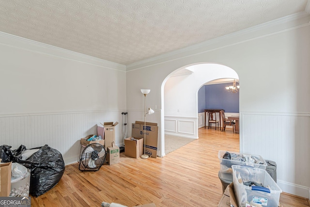 118 Surge Stone Ln, Stockbridge, GA 30281 - spare room with arched walkways, a wainscoted wall, wood finished floors, ornamental molding, and a chandelier