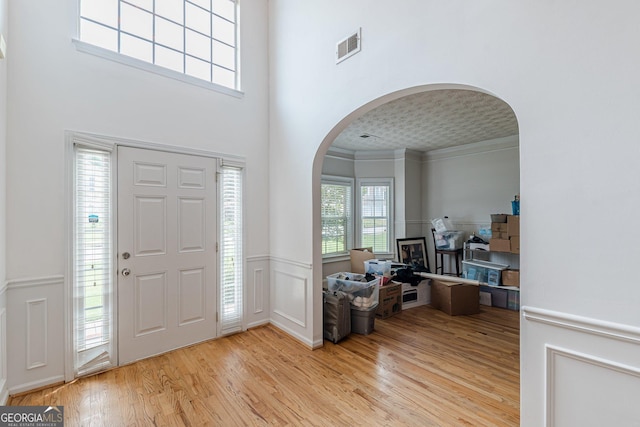 118 Surge Stone Ln, Stockbridge, GA 30281 - foyer entrance with arched walkways, light wood finished floors, a wainscoted wall, and ornamental molding
