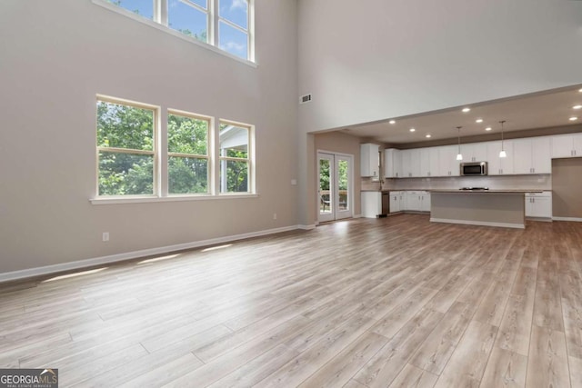 4000 Red Canoe Bnd, Lilburn, GA 30047 - unfurnished living room featuring light wood-style floors, plenty of natural light, baseboards, a towering ceiling, and recessed lighting