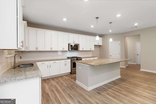 4000 Red Canoe Bnd, Lilburn, GA 30047 - kitchen featuring appliances with stainless steel finishes, a sink, tasteful backsplash, a center island, and white cabinetry
