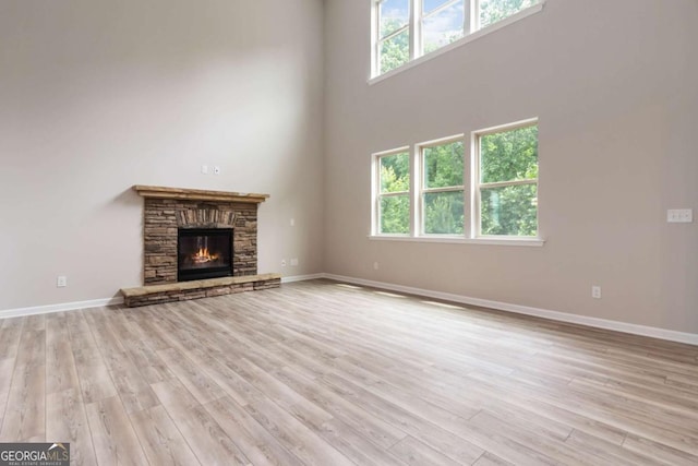 4000 Red Canoe Bnd, Lilburn, GA 30047 - unfurnished living room with wood finished floors, baseboards, a high ceiling, and a stone fireplace
