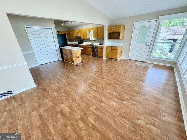 198 Swift Creek Rd, Cordele, GA 31015 - kitchen featuring vaulted ceiling, dishwashing machine, brown cabinets, light countertops, and light wood-style floors