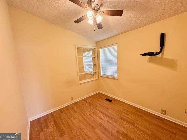 198 Swift Creek Rd, Cordele, GA 31015 - unfurnished room featuring a textured ceiling, wood finished floors, vaulted ceiling, baseboards, and ceiling fan