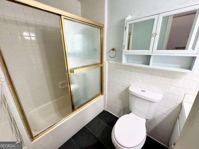 198 Swift Creek Rd, Cordele, GA 31015 - bathroom with toilet, tile patterned floors, enclosed tub / shower combo, tile walls, and wainscoting
