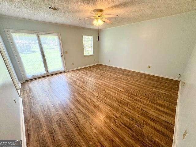 198 Swift Creek Rd, Cordele, GA 31015 - spare room with wood finished floors, ceiling fan, a textured ceiling, and baseboards