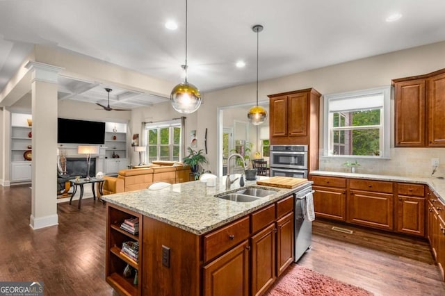 5830 Caveat Ct, Suwanee, GA 30024 - kitchen featuring a ceiling fan, a center island with sink, dark wood-style floors, brown cabinetry, and beam ceiling