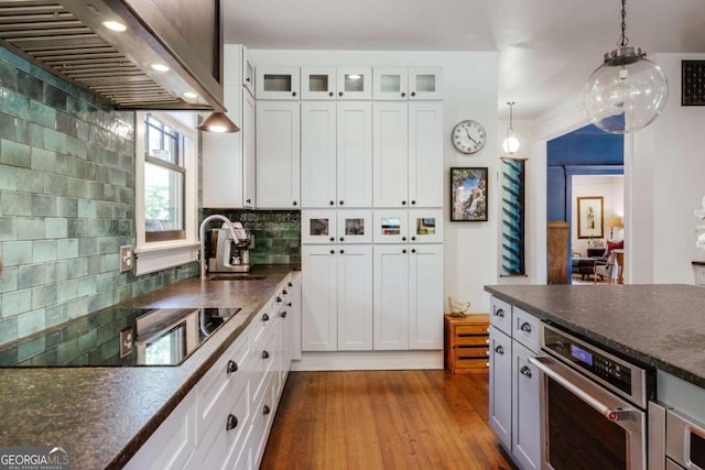 781 Boulevard, Athens, GA 30601 - kitchen featuring black electric cooktop, wall chimney range hood, oven, dark countertops, and dark wood-style floors
