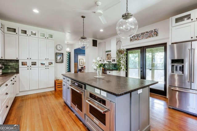 781 Boulevard, Athens, GA 30601 - kitchen featuring appliances with stainless steel finishes, a ceiling fan, light wood finished floors, white cabinetry, and decorative backsplash