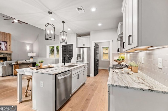 980 Bridge Rd, Ellijay, GA 30540 - kitchen featuring appliances with stainless steel finishes, open floor plan, decorative backsplash, a stone fireplace, and light stone counters