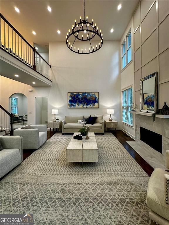 365 Morning Dew Cir, Roswell, GA 30075 - living area featuring a high ceiling, arched walkways, wood finished floors, a fireplace, and baseboards