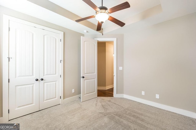 213 Barnyard Way, Perry, GA 31069 - unfurnished bedroom with baseboards, carpet, a closet, a tray ceiling, and a ceiling fan