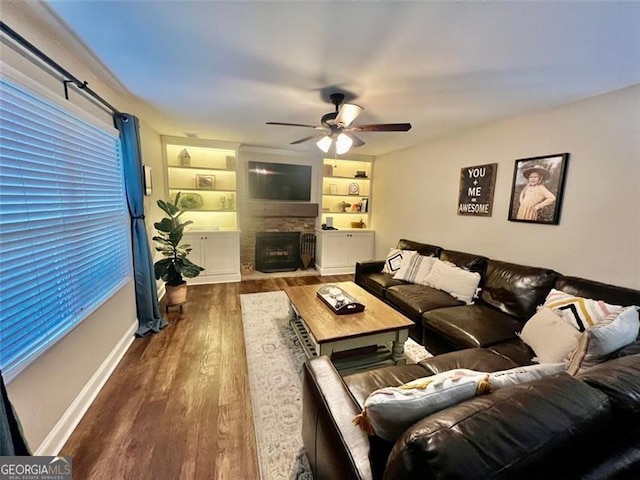 37 Frost Ln, Dawsonville, GA 30534 - living room featuring a ceiling fan, wood finished floors, a stone fireplace, built in shelves, and baseboards