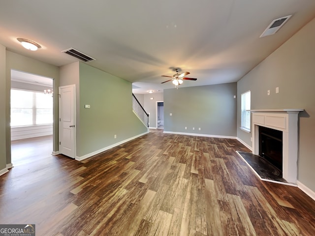 3507 Hideaway Ln, Loganville, GA 30052 - unfurnished living room with a fireplace with raised hearth, dark wood finished floors, ceiling fan, stairs, and baseboards