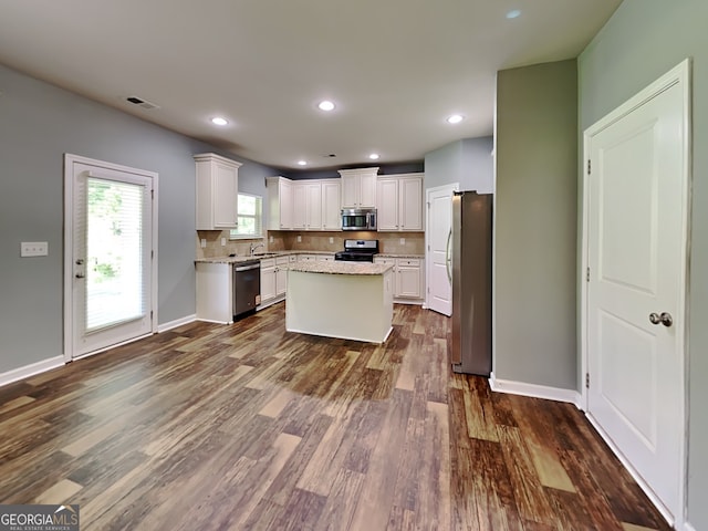3507 Hideaway Ln, Loganville, GA 30052 - kitchen featuring stainless steel appliances, dark wood finished floors, white cabinetry, tasteful backsplash, and a kitchen island
