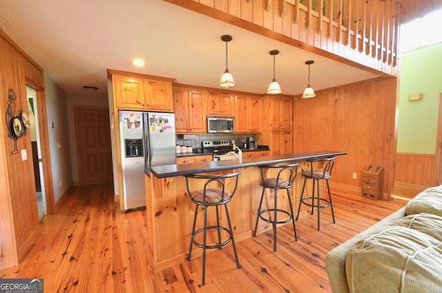2025 Chicken Rd, Dudley, GA 31022 - kitchen with stainless steel appliances, dark countertops, tasteful backsplash, wooden walls, and light wood-style floors