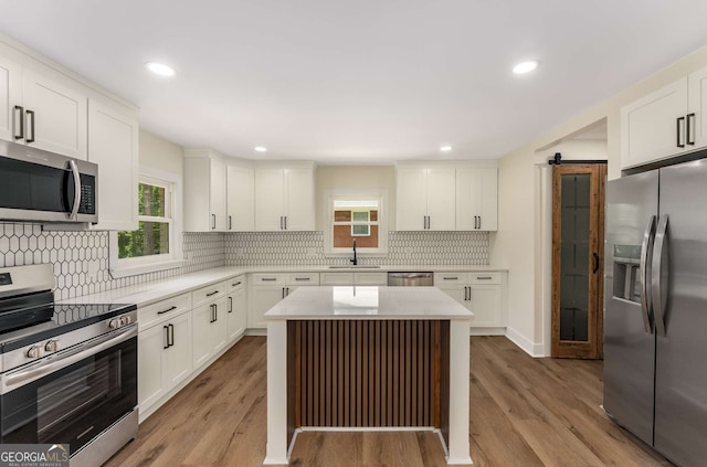 1364 Willis Mill Rd SW, Atlanta, GA 30311 - kitchen featuring appliances with stainless steel finishes, a barn door, a sink, decorative backsplash, and light countertops