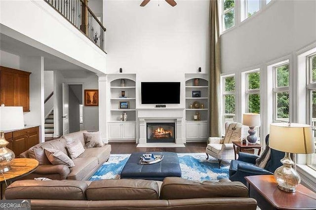 715 Creekside Bnd, Alpharetta, GA 30004 - living area with a high ceiling, ceiling fan, built in shelves, stairway, and a warm lit fireplace