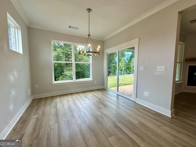 7040 Manchester Dr, Flowery Branch, GA 30542 - unfurnished dining area featuring plenty of natural light, a chandelier, wood finished floors, and crown molding