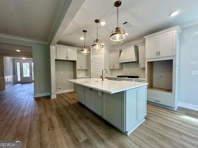7040 Manchester Dr, Flowery Branch, GA 30542 - kitchen featuring custom range hood, crown molding, wood finished floors, gas stovetop, and light stone counters