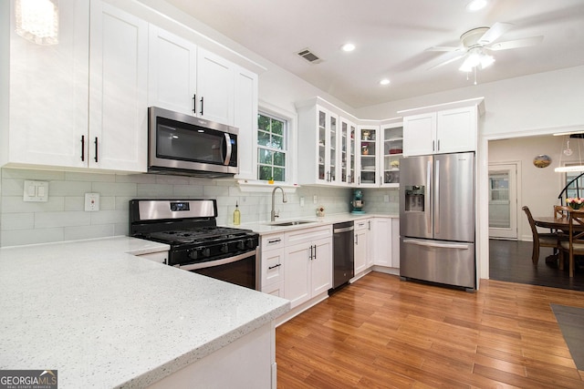 1292 Eubanks Ave, East Point, GA 30344 - kitchen featuring stainless steel appliances, light stone countertops, white cabinetry, decorative backsplash, and glass insert cabinets