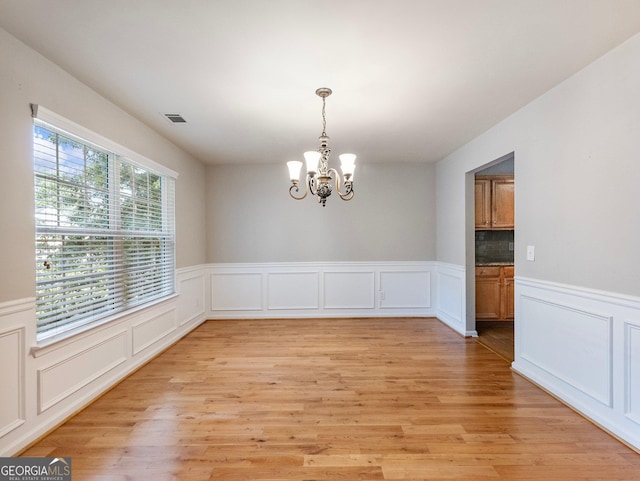 6439 Mossy Boulder Dr, Flowery Branch, GA 30542 - empty room featuring a chandelier, a decorative wall, wainscoting, and light wood-style flooring