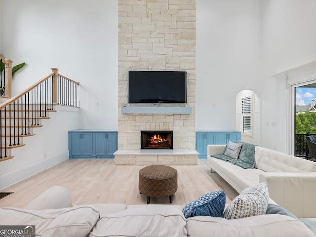 5832 Lula Bridge Ln, Braselton, GA 30517 - living room featuring a stone fireplace, wood finished floors, a high ceiling, stairway, and arched walkways