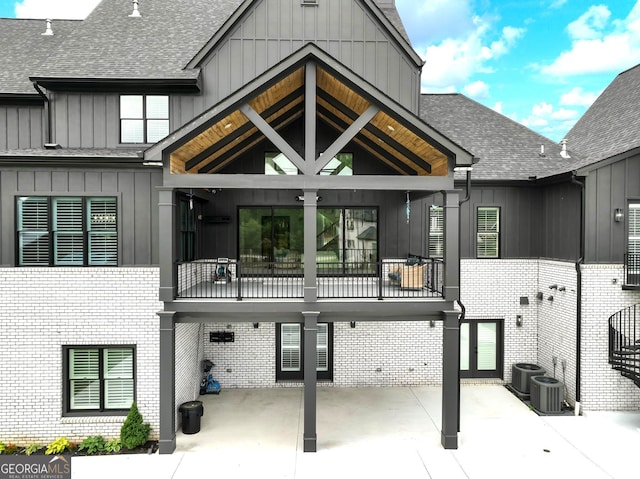 5832 Lula Bridge Ln, Braselton, GA 30517 - back of house featuring board and batten siding, brick siding, roof with shingles, and a balcony
