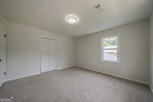 4732 Manly Ct, Stone Mountain, GA 30088 - unfurnished bedroom featuring carpet floors, a closet, baseboards, and a textured ceiling